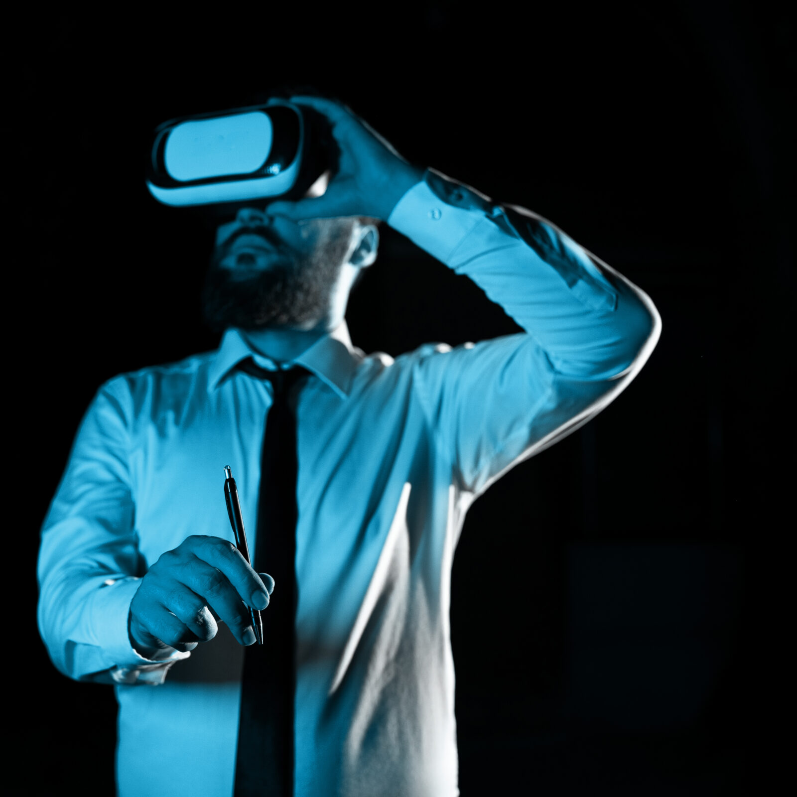 Standig Man Holding Pen To Point Important Messages And Wearing Vr Glasses. Businessman Having Virtual Reality Eyeglasses And Pointing On Crutial Informations.
